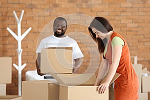 Interracial couple unpacking boxes indoors. Moving into new house