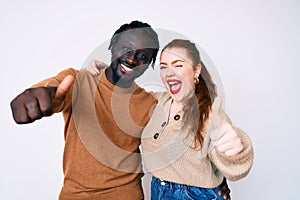 Interracial couple wearing casual clothes approving doing positive gesture with hand, thumbs up smiling and happy for success