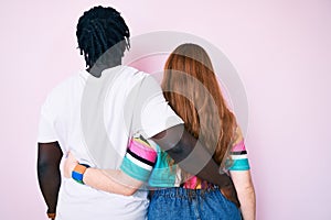 Interracial couple wearing casual clothes hugging oneself happy and positive from backwards