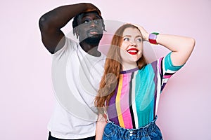 Interracial couple wearing casual clothes smiling confident touching hair with hand up gesture, posing attractive and fashionable