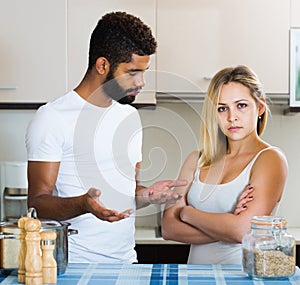 interracial family couple with serious faces quarrelling in kitchen