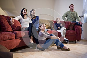 Interracial family sitting on sofa watching TV