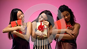 Interracial females in pajamas holding gift, celebrating holiday, happiness