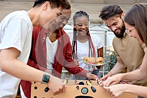 Interracial Friends play kicker table football outdoors in backyard during bbq party