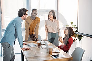 interracial group of business colleagues discussing work during coffee break at workplace