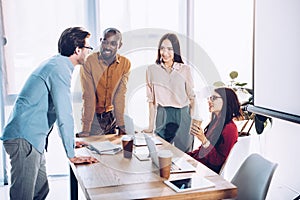 interracial group of business colleagues discussing work during coffee break at workplace