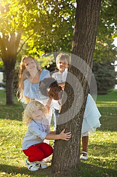 Interracial group of kids, girls and boys playing together at the park in summer day