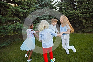 Interracial group of kids, girls and boys playing together at the park in summer day