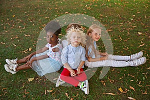 Interracial group of kids, girls and boys playing together at the park in summer day