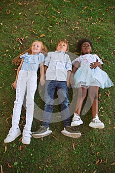 Interracial group of kids, girls and boys playing together at the park in summer day