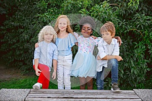 Interracial group of kids, girls and boys playing together at the park in summer day