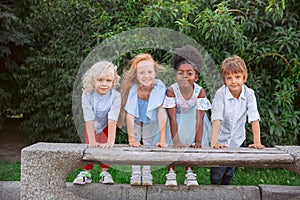 Interracial group of kids, girls and boys playing together at the park in summer day