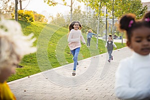 Interracial group of kids, girls and boys playing together at the park in summer day