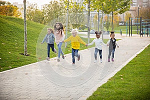 Interracial group of kids, girls and boys playing together at the park in summer day