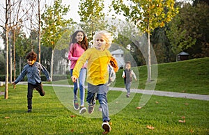 Interracial group of kids, girls and boys playing together at the park in summer day