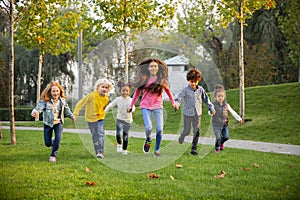 Interracial group of kids, girls and boys playing together at the park in summer day