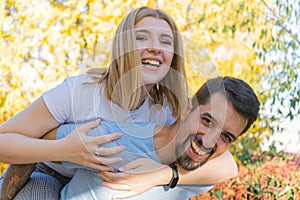 Interracial heterosexual happy couple playing and laughing with vitality. Latino boyfriend carrying in piggy back to his caucasian