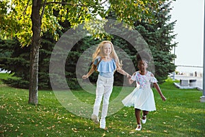 Interracial kids, friends, girls playing together at the park in summer day