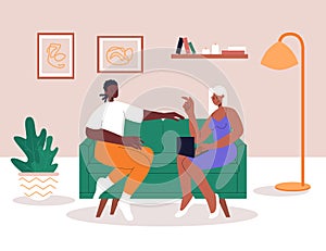 Interracial lesbian couple relaxing on comfy sofa in living room. Spending time together in apartment. Woman with laptop