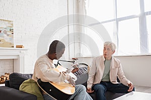 Interracial pensioners playing acoustic guitar on