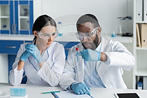 Interracial scientists in safety goggles holding