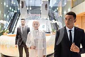 interracial security men escorting senior businesswoman