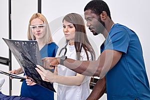 interracial team of doctors look and discuss X-ray or MRI scan of the patient s brain