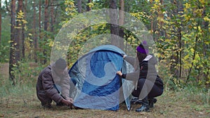 Interracial travelers couple setting up camp tent