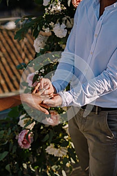 Interracial wedding couple - African-American bride and Caucasian groom. Groom puts a ring on brides finger. Destination