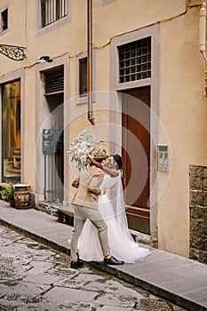 Interracial wedding couple. Wedding in Florence, Italy. African-American bride and Caucasian groom kiss on the street.