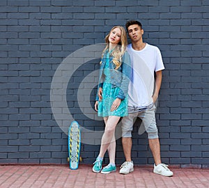 Interracial young couple in love outdoor whis skateboard. Stunning sensual outdoor portrait of young stylish fashion couple posing