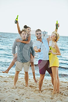 interracial young friends with beer taking selfie