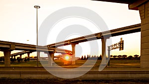 Intersection of elevated highway at sunset with bright sunset shining thru pillars