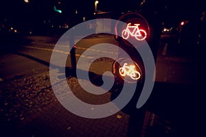 intersection at night with traffic light for a cycling lane showing red and yellow bicycle symbol in dark light mood