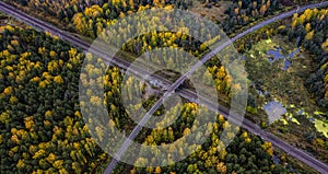 Intersection of railway tracks in swamp and autumn forest, a bird`s-eye view from drone