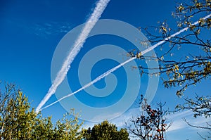 The intersection of the trail from the planes in the bright blue sky