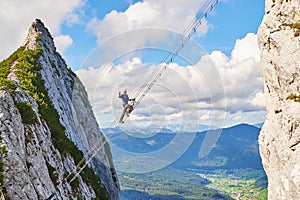 Intersport Donnerkogel via ferrata in Summer, with a man showing a victory sign while climbing the diagonal ladder.