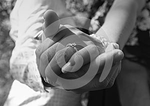 Intertwined hands of wedding couple with engagement ring as main object