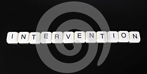 Intervention text word title caption label cover backdrop background. Alphabet letter toy blocks on black reflective background. W photo