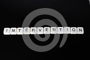 Intervention text word title caption label cover backdrop background. Alphabet letter toy blocks on black reflective background. W photo