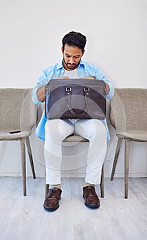 Interview, man and job in waiting room, briefcase and looking for cv in bag by wall background. Business person, search