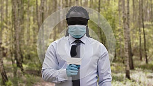 Interview shot. African reporter with face medical mask and gloves in the forest