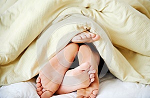 Intimacy under the covers. Cropped shot of a couples feet poking out from under the bedsheets.