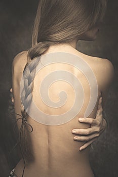Intimate woman portrait bare back and long braid