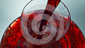 Intoxicant red beverage filling decanter slow motion. Wine forms waves glassware