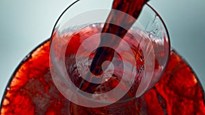 Intoxicant red beverage filling decanter slow motion. Wine forms waves glassware