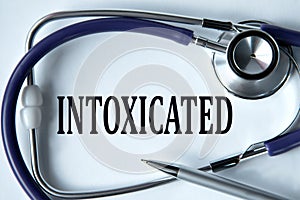 INTOXICATED - word on white background with pen and stethoscope