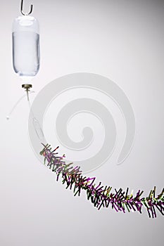 Intravenous drip with tinsel attached to it. Conceptual image