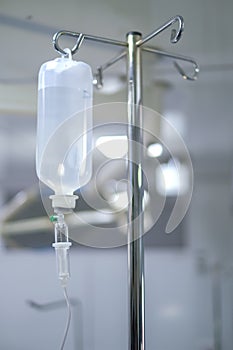 Intravenous or Iv fluids drip bottle hanging on a metal pole in hospital emergency room