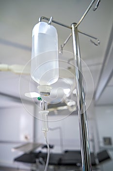 Intravenous or Iv fluids drip bottle hanging on a metal pole in hospital emergency room